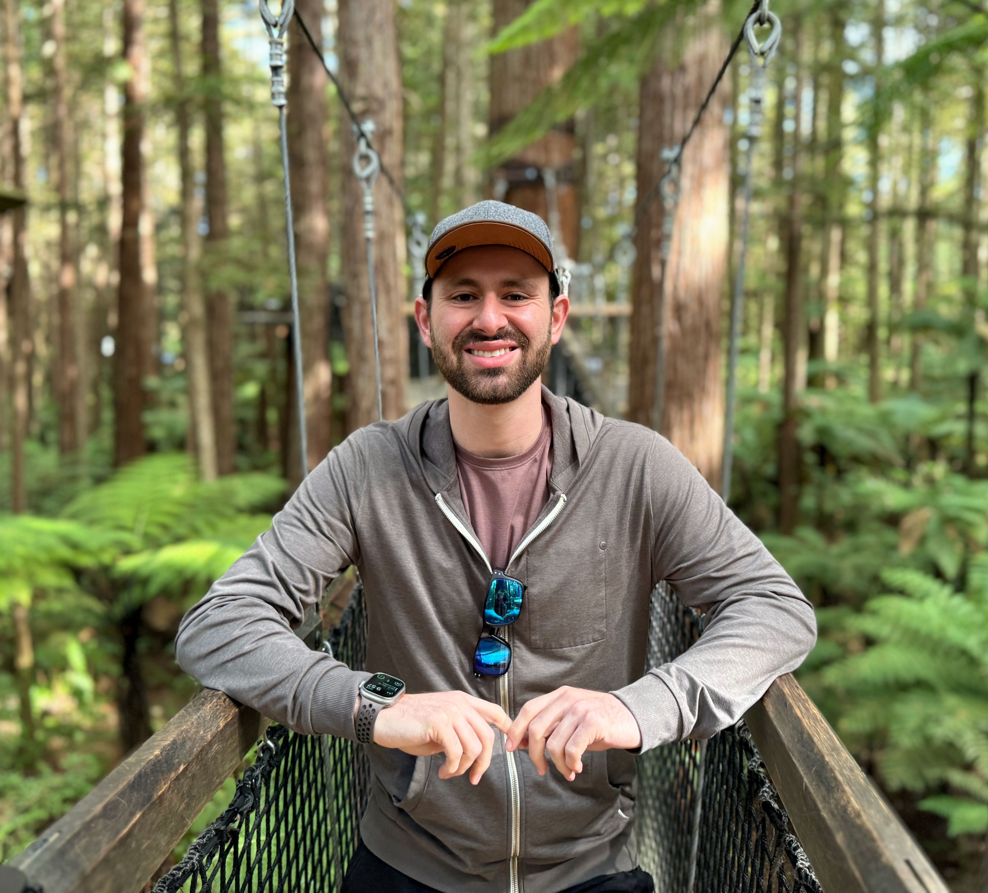 Dean standing in a forest of California Redwood trees in New Zealand